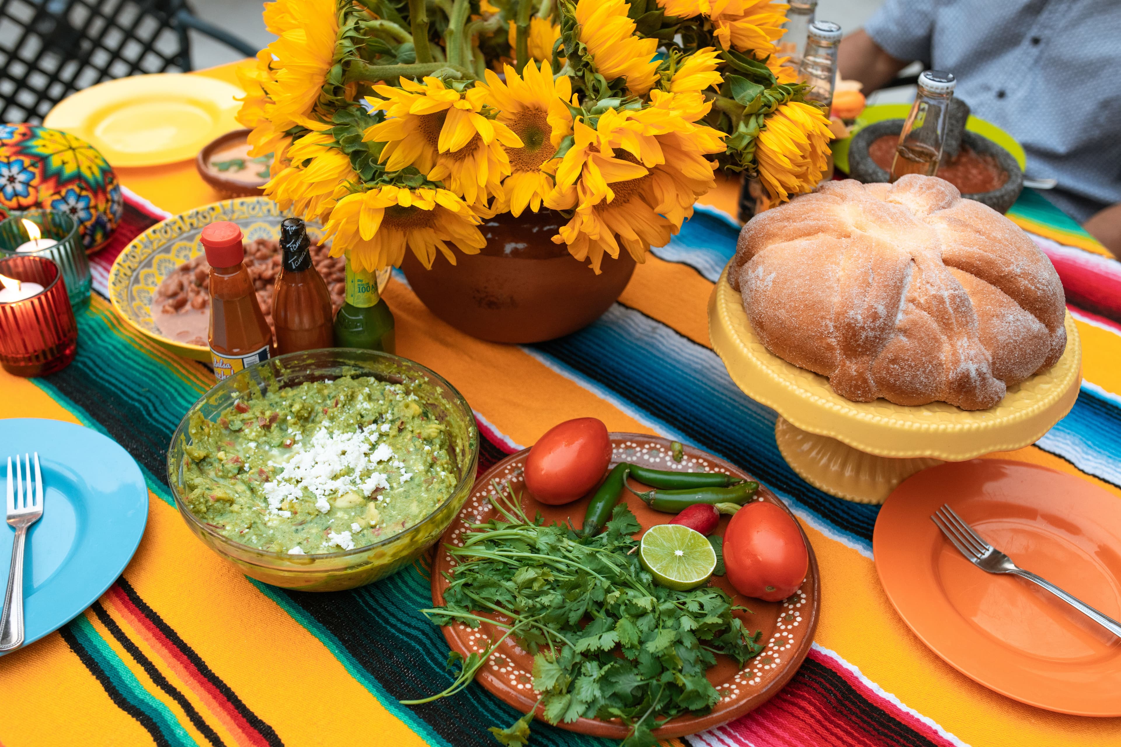 Mesa con mantel de sarape, girasoles, guacamole y pan de muerto